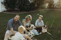 A family of four, doing what they enjoy most during their family portrait session - hanging out in the backyard and playing with their dogs. 