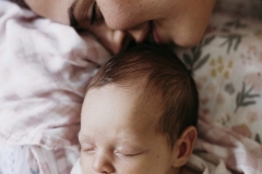 A mother kisses the head of her newborn baby.
