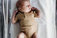 A days old newborn baby in a clear bassinet at the hospital.