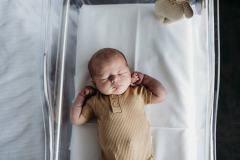 A newborn baby is days old, lies asleep in his clear bassinet in hospital in Rockhampton.