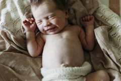 A newborn baby smiles as she snuggles on her parent's bed at their home in Rockhampton.