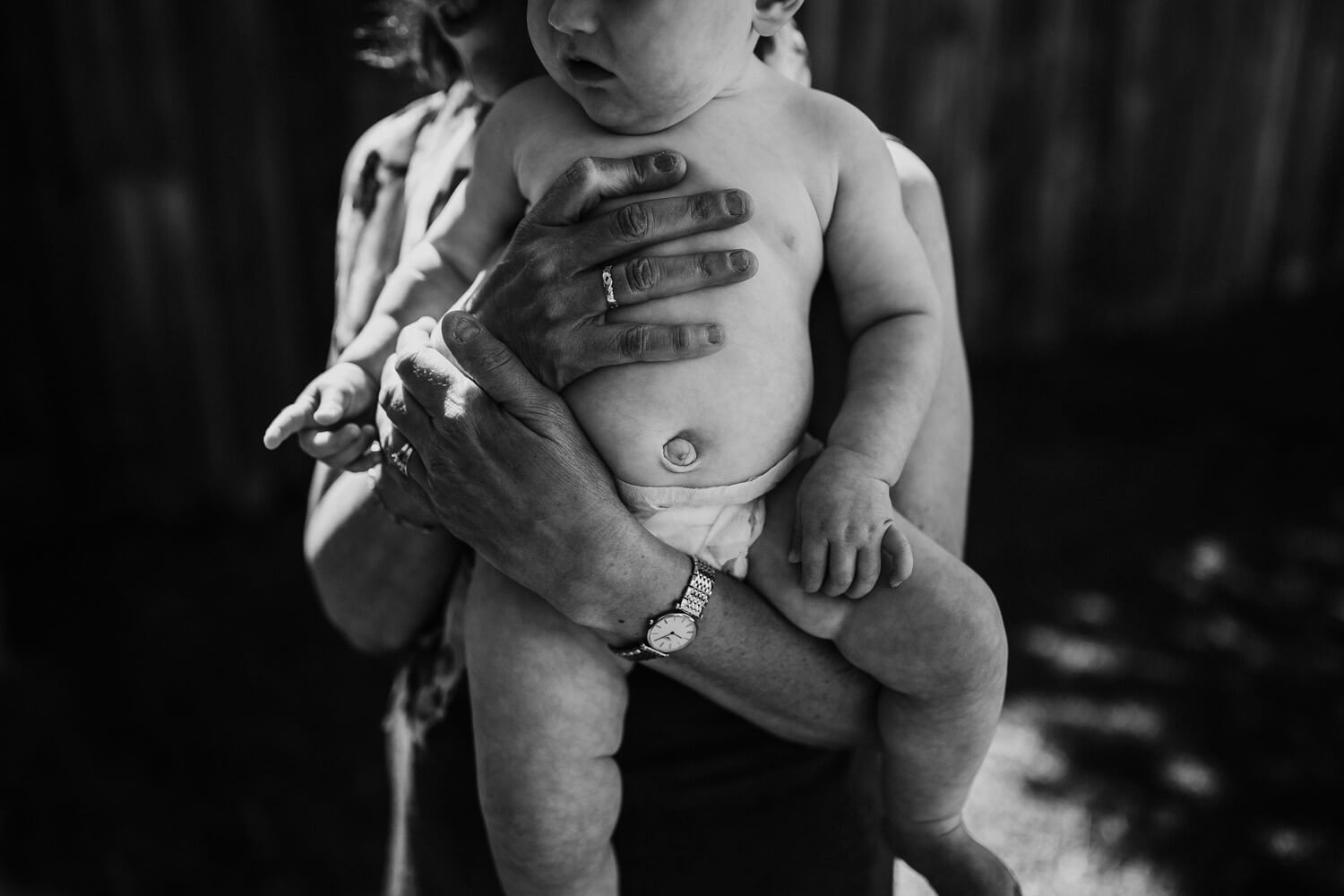 Murphy family A black and white images of a woman's hands holding onto a baby. Only the babies belly is visible.