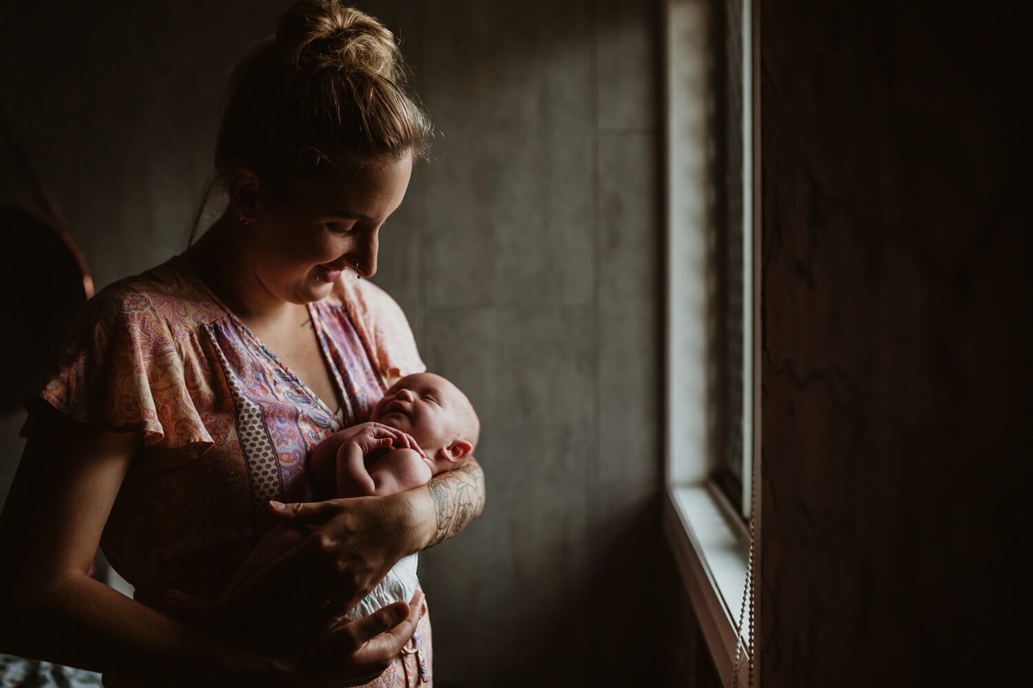 Murphy family A newborn is held by its mother as light streams through the window.