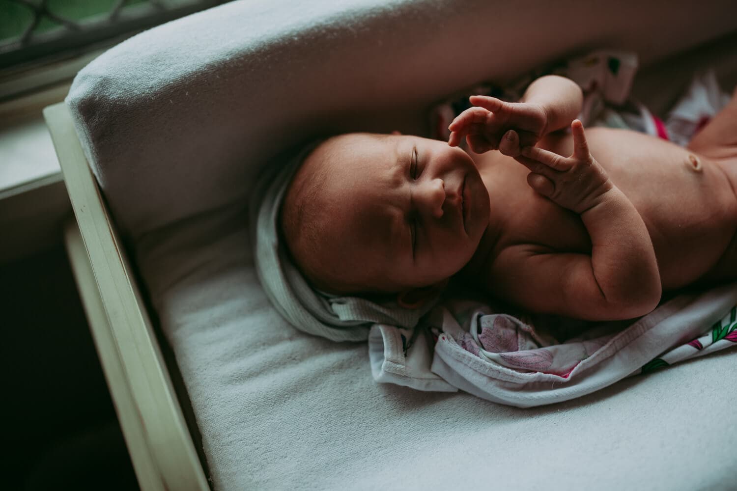 Murphy family A newborn lies on a change mat, bringing its hands to its face.