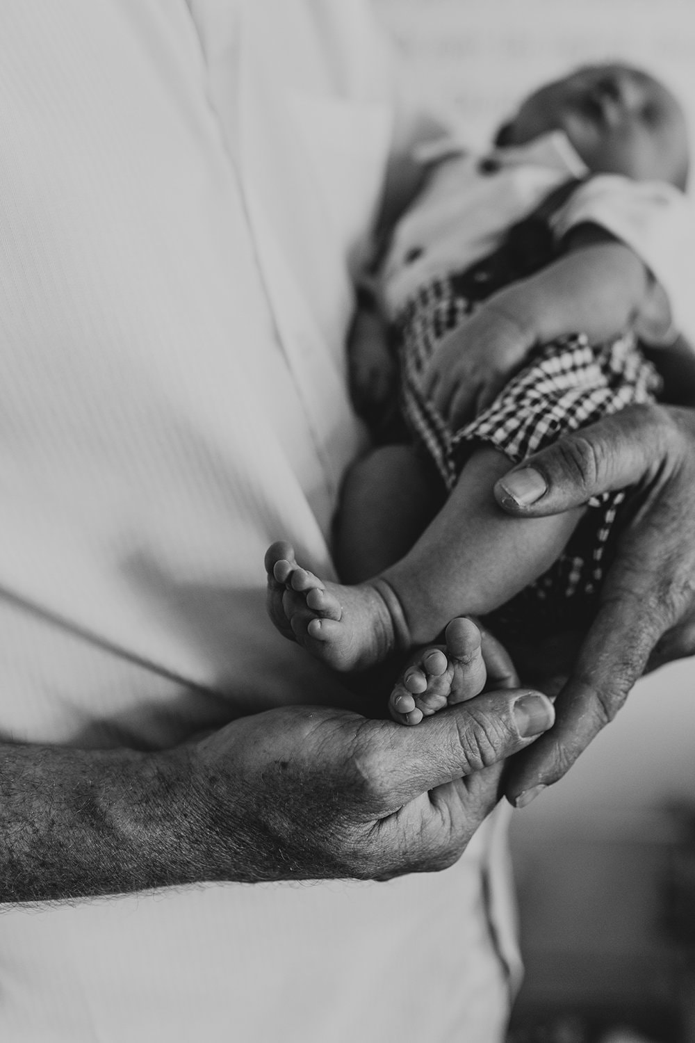 Murphy family A newborn baby's feet are held by his father's hand. The image is black and white.