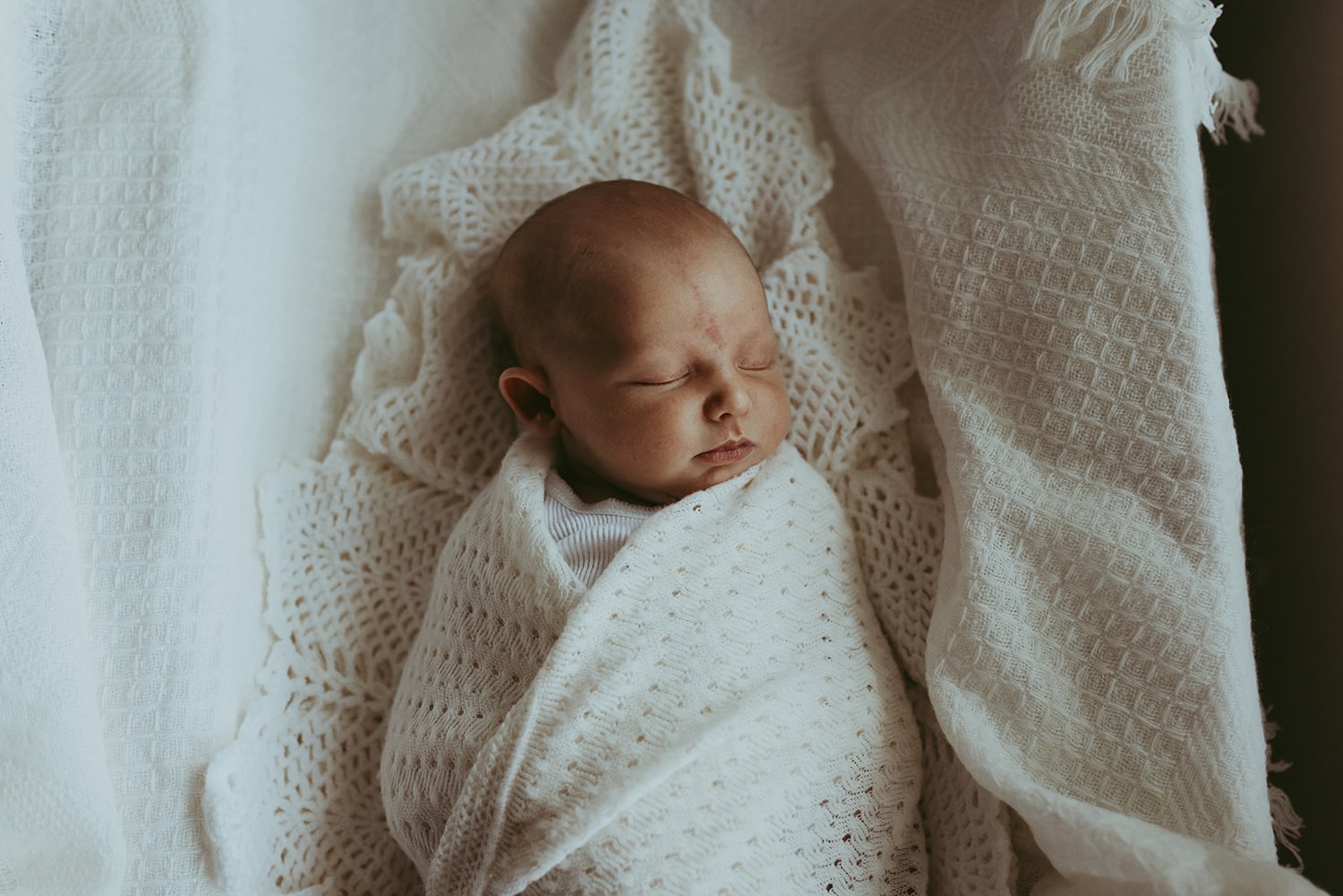 Murphy family A newborn baby is wrapped in a cream heirloom blanket.