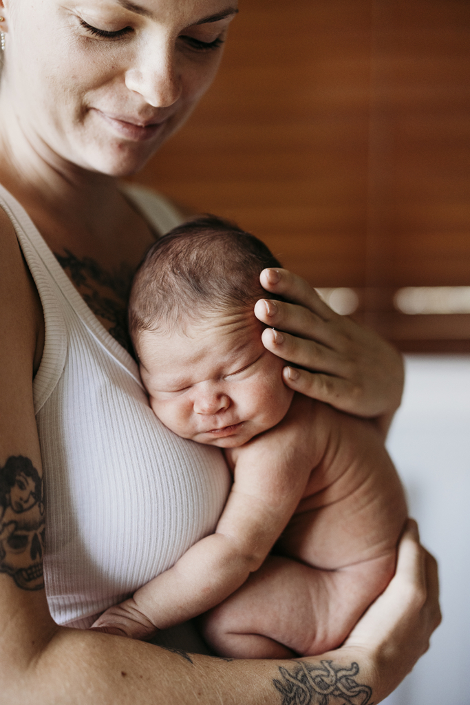 A mother holds her newborn baby against her chest and has some precious skin-on-skin time.