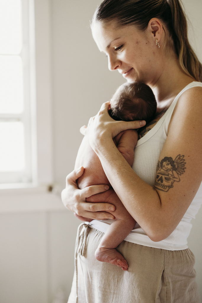 A mother holds her newborn baby against her chest as they share skin-on-skin.