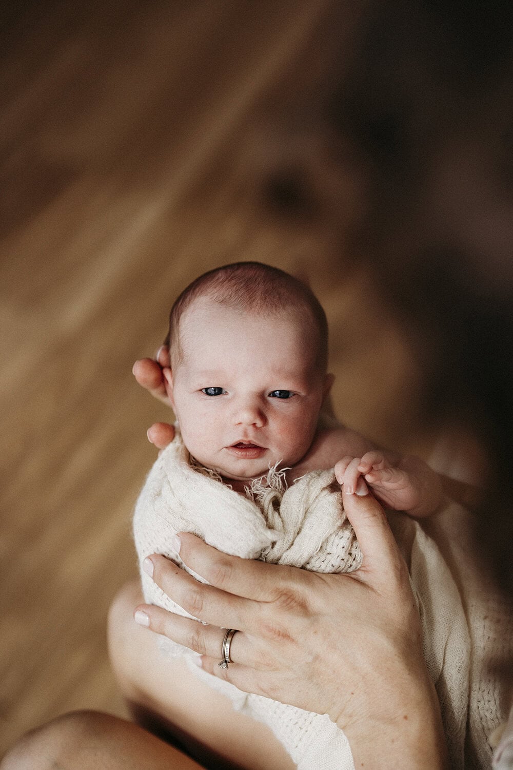 Studio newborn session Rockhampton A newborn baby is held by her mother as she stares up at the camera.
