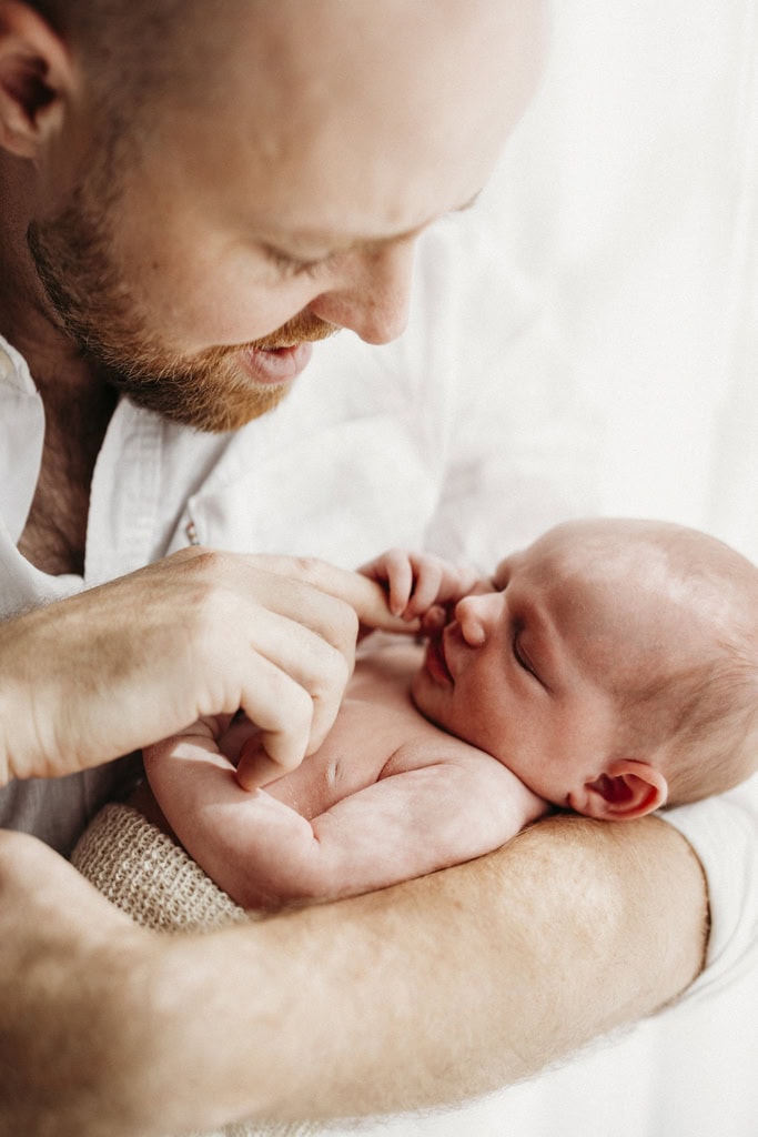 A father holds his newborn baby in his arms.