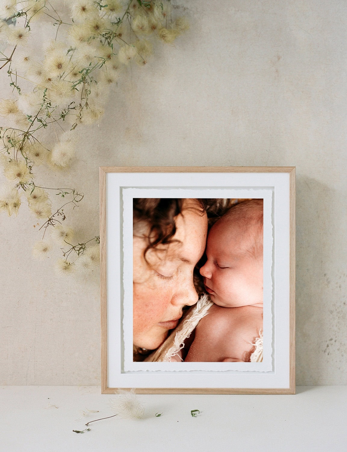 Studio portrait sessions with your newborn A fine art timber frame with a photo of a mother and her newborn baby.