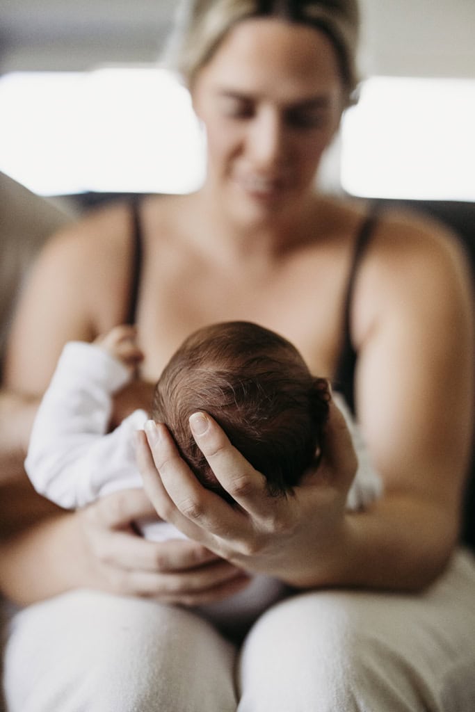 A mother cradles her newborn baby's head in her hands.