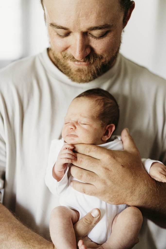 A father looks down at his newborn daughter and smiles.