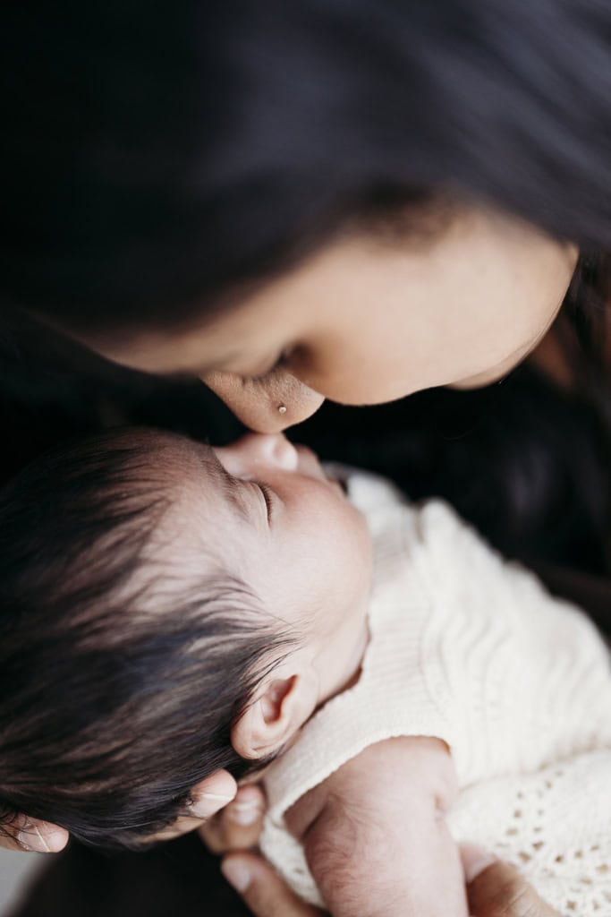 A mother touches noses with her newborn daughter.
