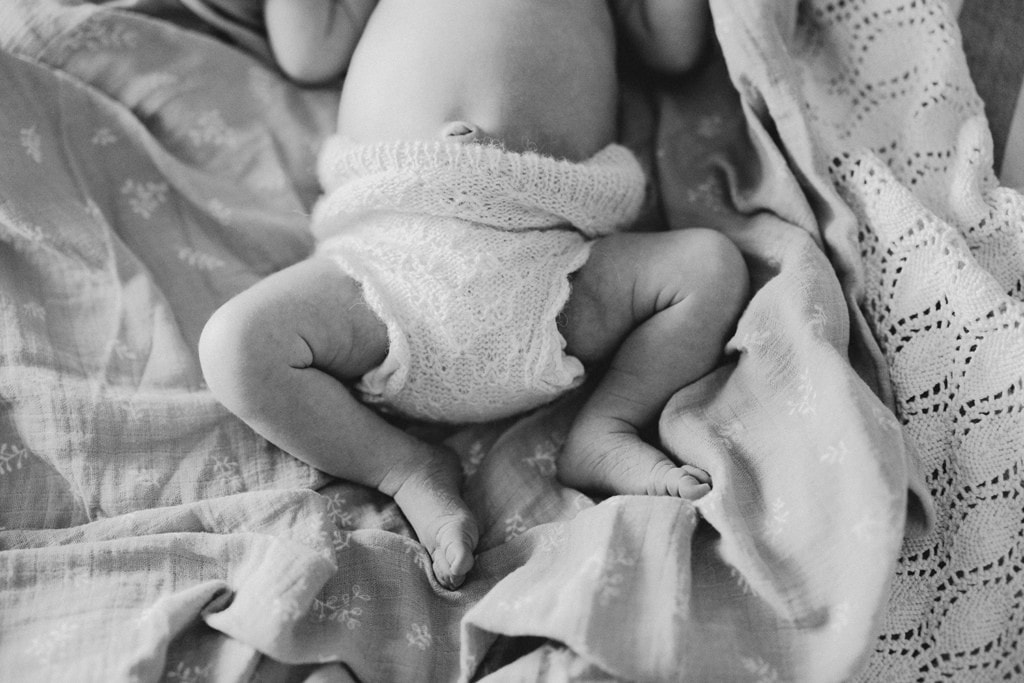 A newborn baby's legs lay curled up as she sleeps.