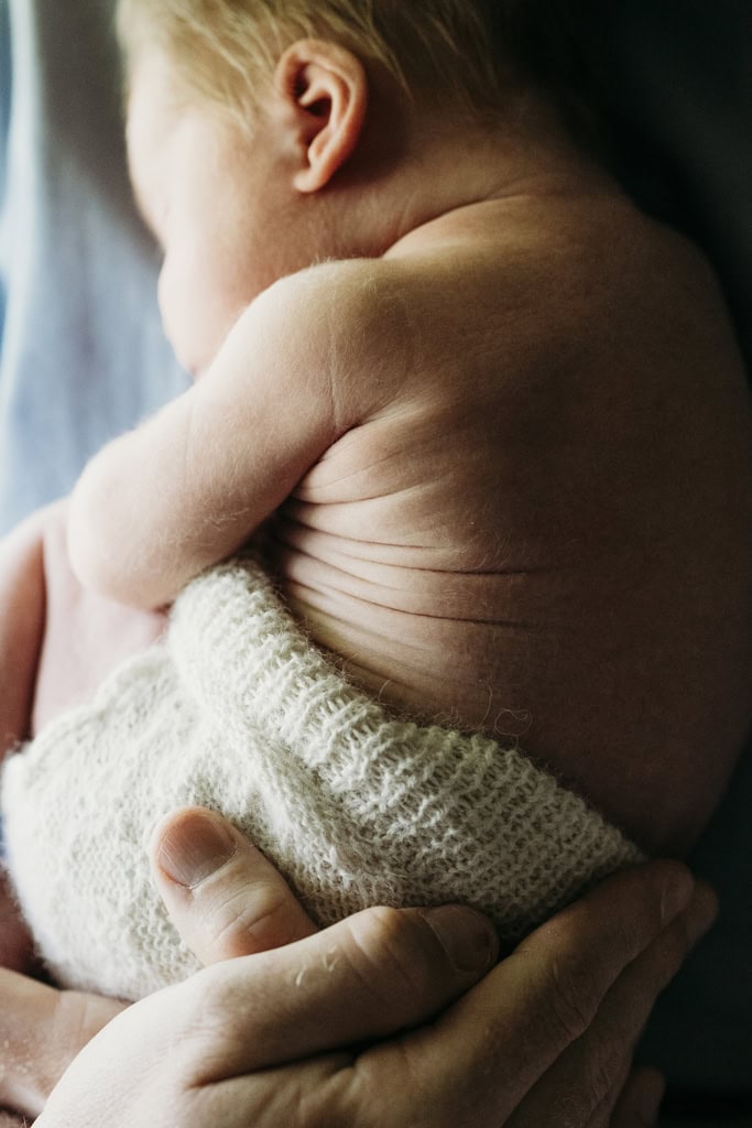 A newborn snuggles into his dad's chest as his skin wrinkles.