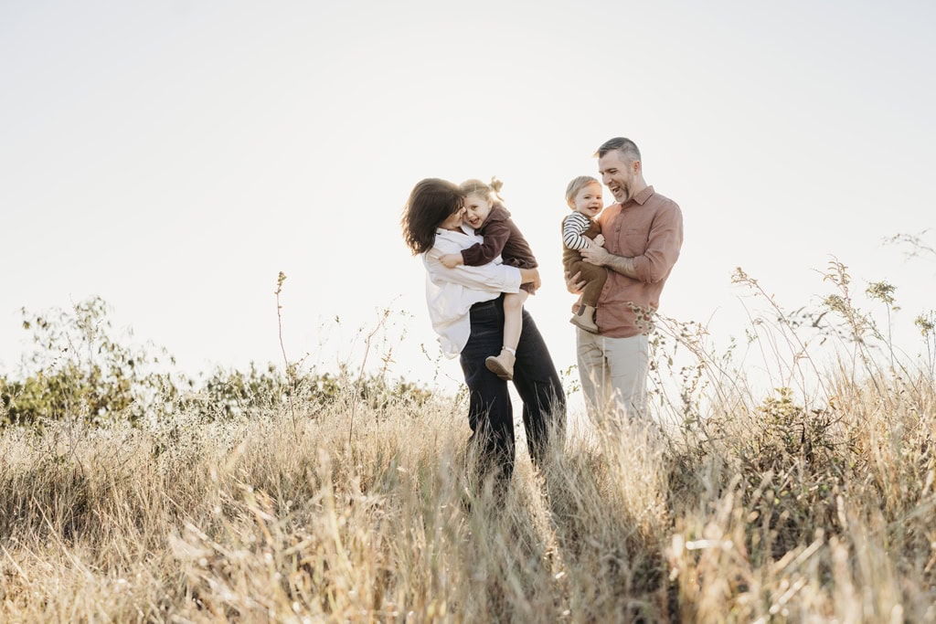 A family of four cuddle and laugh with each other.