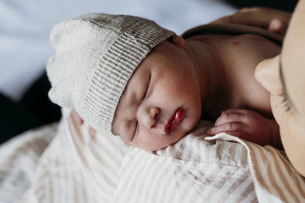 A baby sleeps on his mother's shoulder at hospital.
