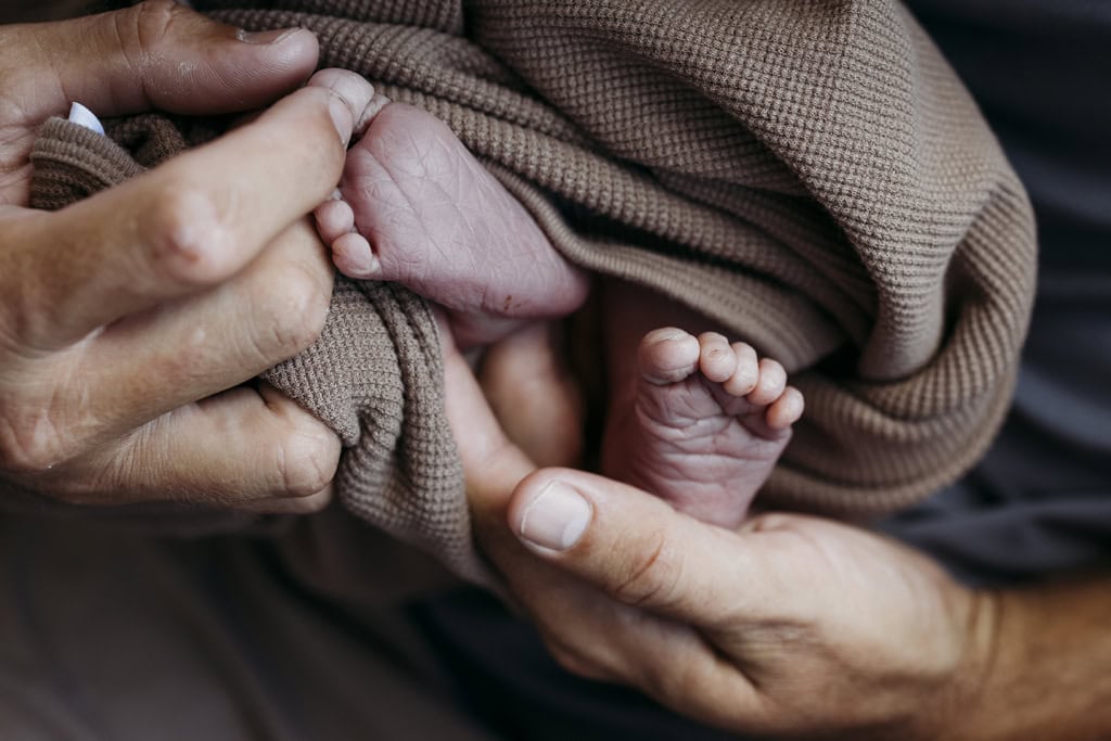A dad holds his newborn baby's feet.