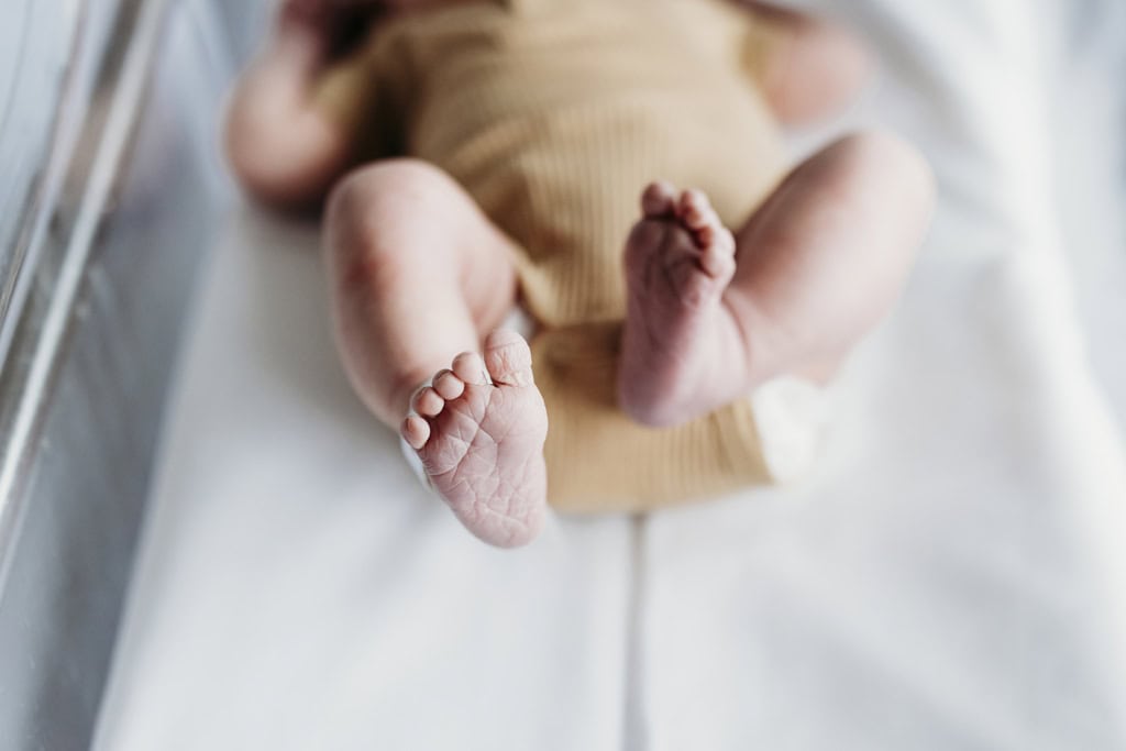 A newborn baby's feet as he wriggles in his clear bassinet.
