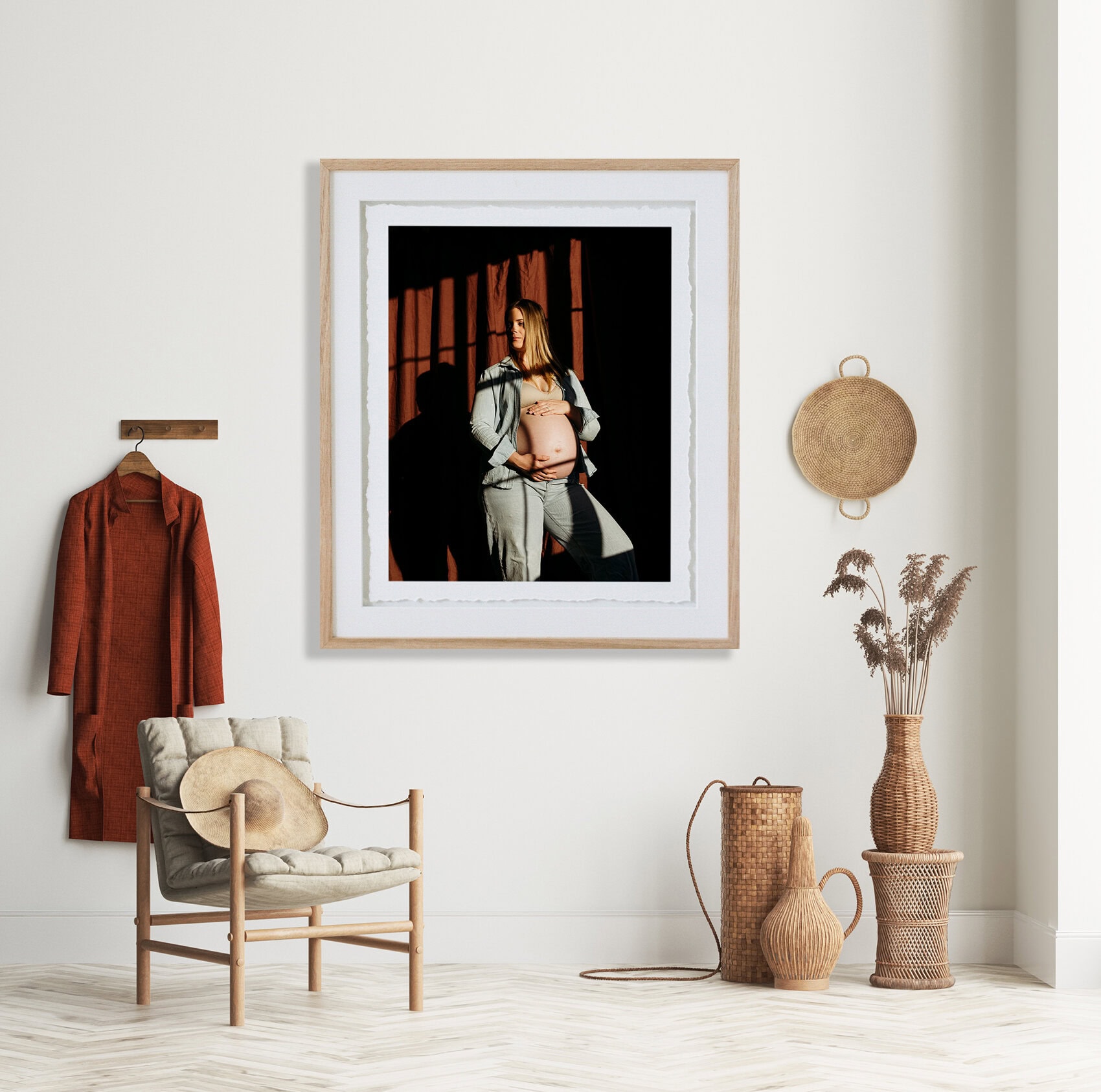 A framed portrait of a pregnant woman hangs on the wall above a chair.