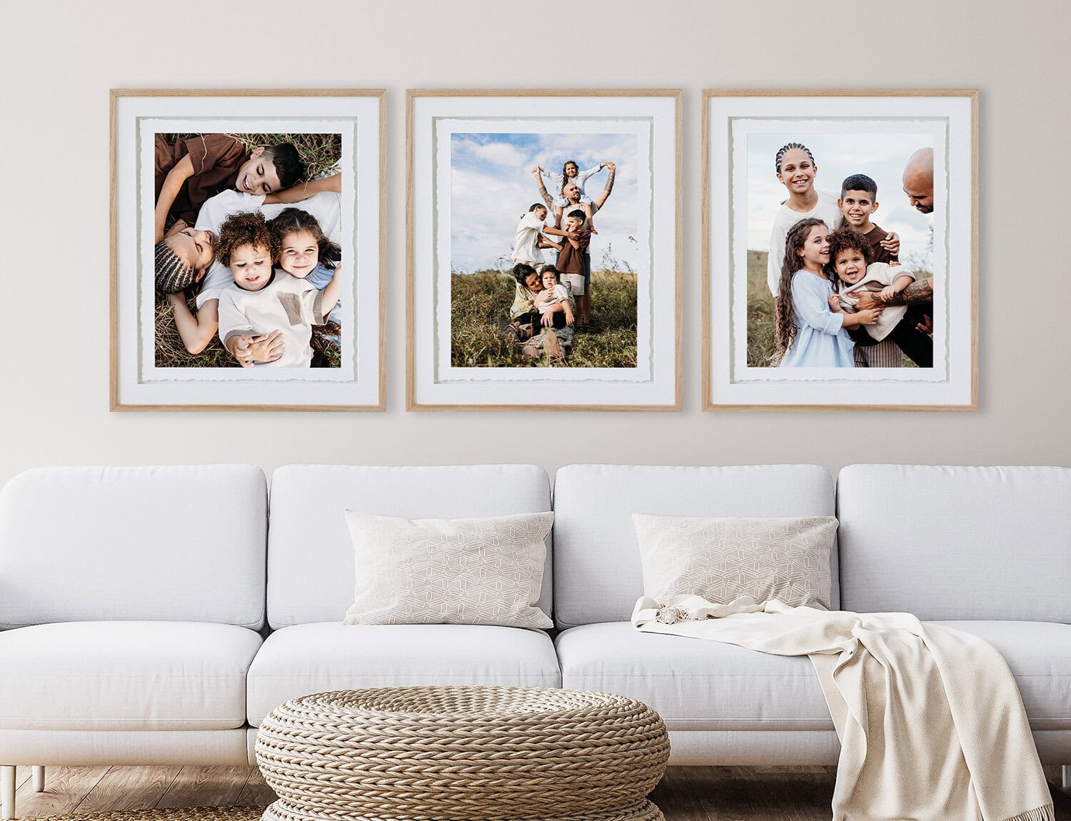 A set of three frames hangs above a couch. Each portrait is of a family.